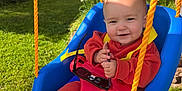 Jimmy is registered to the contest to win money with this photo: baby, barefoot, blue_swing, child, daylight, garden, grass, greenery, happy, infant, nature, orange_clothing, outdoor, person, playground, rope, smiling, sunglasses, sunlight, swing