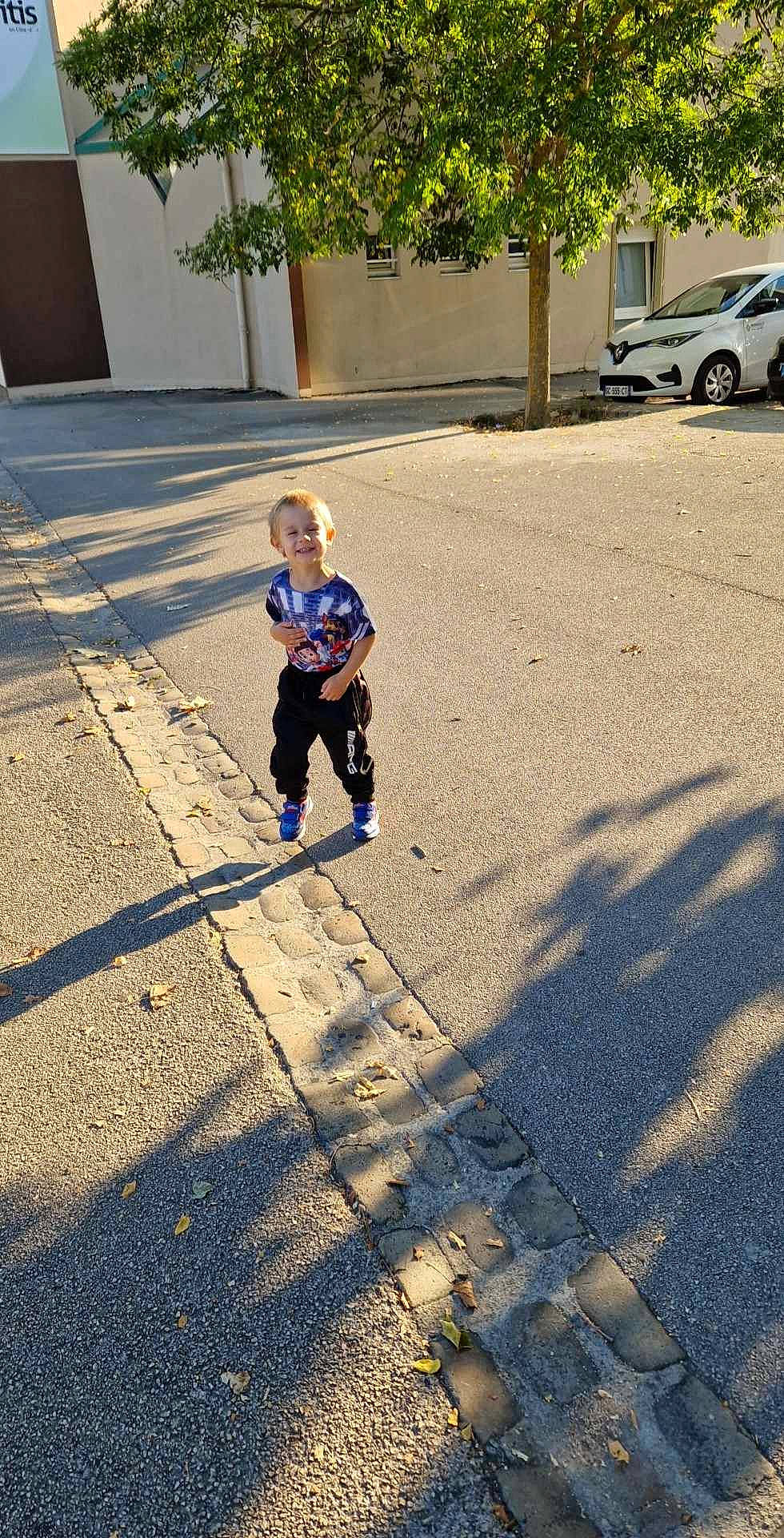 Allan participe au concours pour gagner de l'argent avec cette photo : asphalt, city, electric_blue, flooring, grass, joy, landscape, leg, leisure, person, plant, recreation, road, road_surface, shoe, sidewalk, sunlight, tints_and_shades, tire, toddler