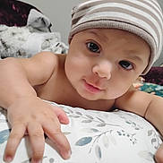 Emiliano joined the competition — help win amazing prizes! baby, child, striped_hat, hand, pillow, blanket, face, eyes, indoor, closeup, infant, curious, cute, person, soft_lighting, skin, expression, cozy, bedroom, comfort