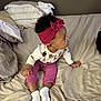 Talaija joined the competition — help win amazing prizes! baby, bed, bedding, casual_clothing, child, cozy, curious, curly_hair, floral_pattern, headband, indoor, long_sleeve_shirt, looking_sideways, person, pillow, pink_pants, red_headband, sitting, toddler, white_socks