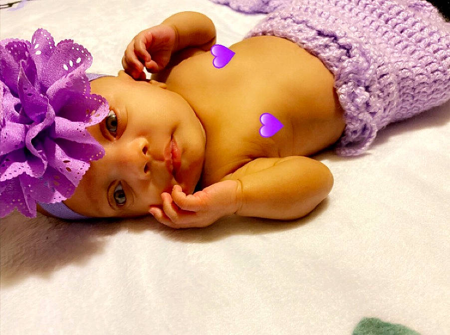 Nola is registered to the contest to win money with this photo: abdomen, baby, baby_products, baby_toddler_clothing, cheek, child, costume_accessory, cut_flowers, eyelash, hair_accessory, lavender, lip, nail, person, petal, pink, purple, skin, stomach, toddler