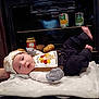 Eric is registered to the contest to win money with this photo: baby, infant, thanksgiving, oven, potatoes, canned_food, blanket, clothing, hat, kitchen, food, person, cute, indoor, lying_down, soft_texture, holiday, autumn, baby_girl, cozy