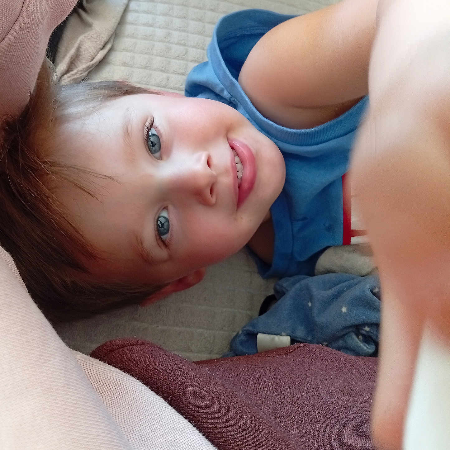 Melvin a rejoint le concours — aidez-le/la à gagner de superbes lots ! blanket, blue_eyes, candid, casual_clothing, child, closeup, comfort, fabric, face, hair, happy, head, indoor, lying_down, person, playful, skin, smiling, soft, toddler