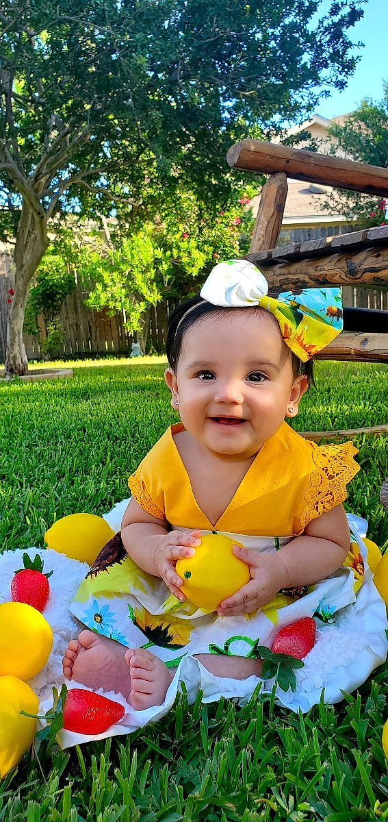 Amiyah is registered to the contest to win money with this photo: baby, botany, child, fun, grass, green, happy, headwear, joy, leaf, leisure, nature, people, people_in_nature, person, plant, recreation, smile, summer, toddler
