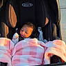 baby, infant, child, stroller, blanket, pink_blanket, plaid, sleeping, face, portrait, outdoor, sunlight, sidewalk, walkway, car_seat, harness, newborn, cozy, black_stroller, street