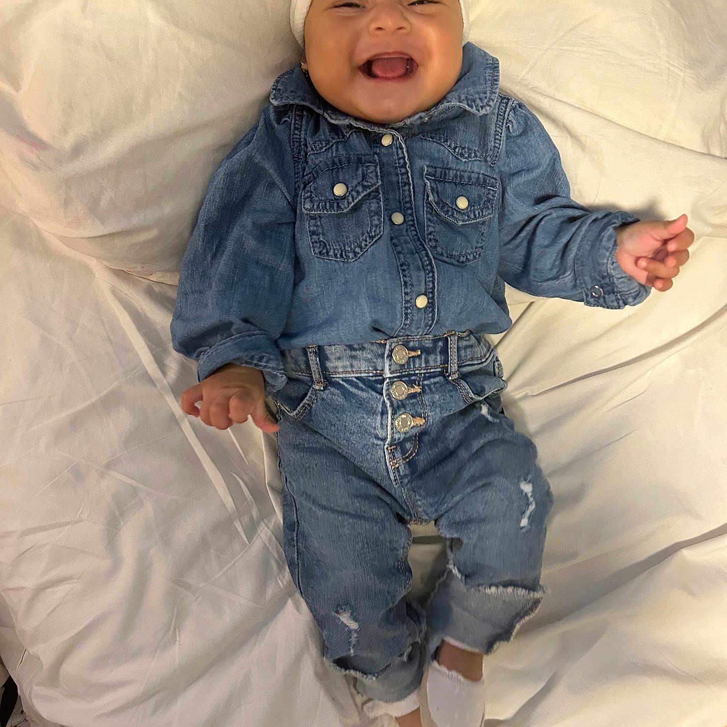 Keylee is registered to the contest to win money with this photo: baby, baby_girl, child, clothing, cute, denim, fashion, footwear, happy, headband, indoor, infant, jeans, person, portrait, shirt, shoes, smiling, toddler, white_bed