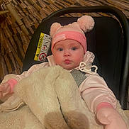 Laylah joined the competition — help win amazing prizes! baby, child, beanie, pink, mittens, blanket, car_seat, pacifier, face, indoor, cute, warm_clothing, expression, person, soft_texture, cozy, infant, headwear, seated, portrait