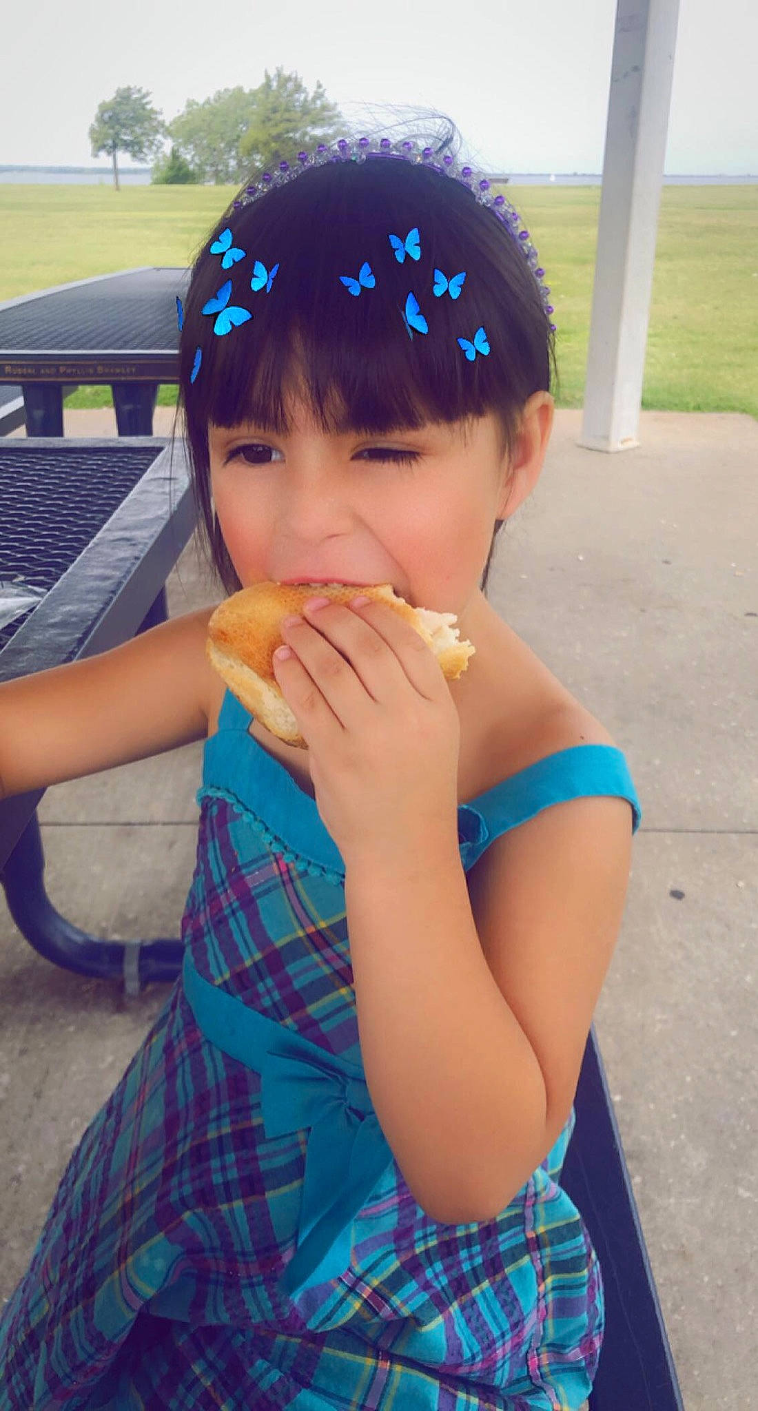 Aubrie joined the competition — help win amazing prizes! bangs, biting, clothing, day_dress, eating, fast_food, finger, food_craving, hair_accessory, hand, headband, headpiece, outdoor_furniture, pattern, person, plaid, snack, sweetness, tartan, taste