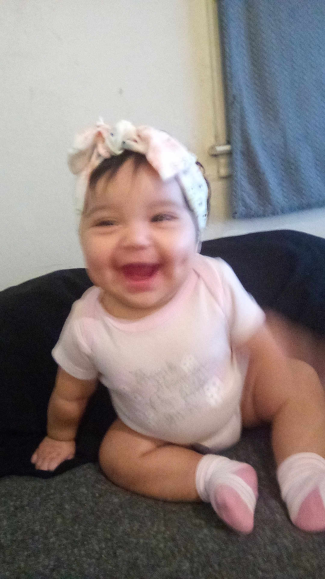 Luna is registered to the contest to win money with this photo: baby, child, smiling, headband, pink_socks, sitting, indoor, cute, happy, infant, clothing, face, person, floor, sock, hand, leg, toddler, blurred, joyful