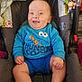 baby, child, car_seat, blue_clothing, smiling, happy, indoor, cute, infant, person, face, sitting, plush_toy, clothing, hand, foot, head, toy, seat_belt, car_seat_padding