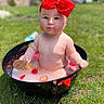 baby, child, red_bow, strawberries, black_tub, milk_bath, grass, outdoor, cute, portrait, summer, water, fruit, sitting, infant, nature, headwear, expression, skin, daylight