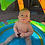 Beckham is registered to the contest to win money with this photo: baby, child, infant, pool, water, inflatable_pool, toy, rubber_duck, outdoor, sunlight, deck, summer, play, bare_skin, sitting, green, yellow, blue, cute, happy