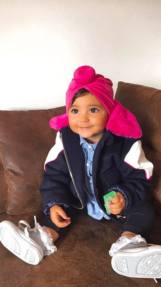 Mya participe au concours pour gagner de l'argent avec cette photo : baby, bonnet, child, child_model, comfort, costume_accessory, costume_hat, couch, cross_training_shoe, eye, headwear, hood, joy, living_room, nose, outdoor_shoe, person, tennis_shoe, toddler, walking_shoe