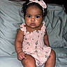 Wavie is registered to the contest to win money with this photo: baby, child, girl, headband, bow, pink, dress, floral, sitting, couch, indoor, portrait, cute, curly_hair, skin, person, infant, expression, looking_at_camera, soft_furniture