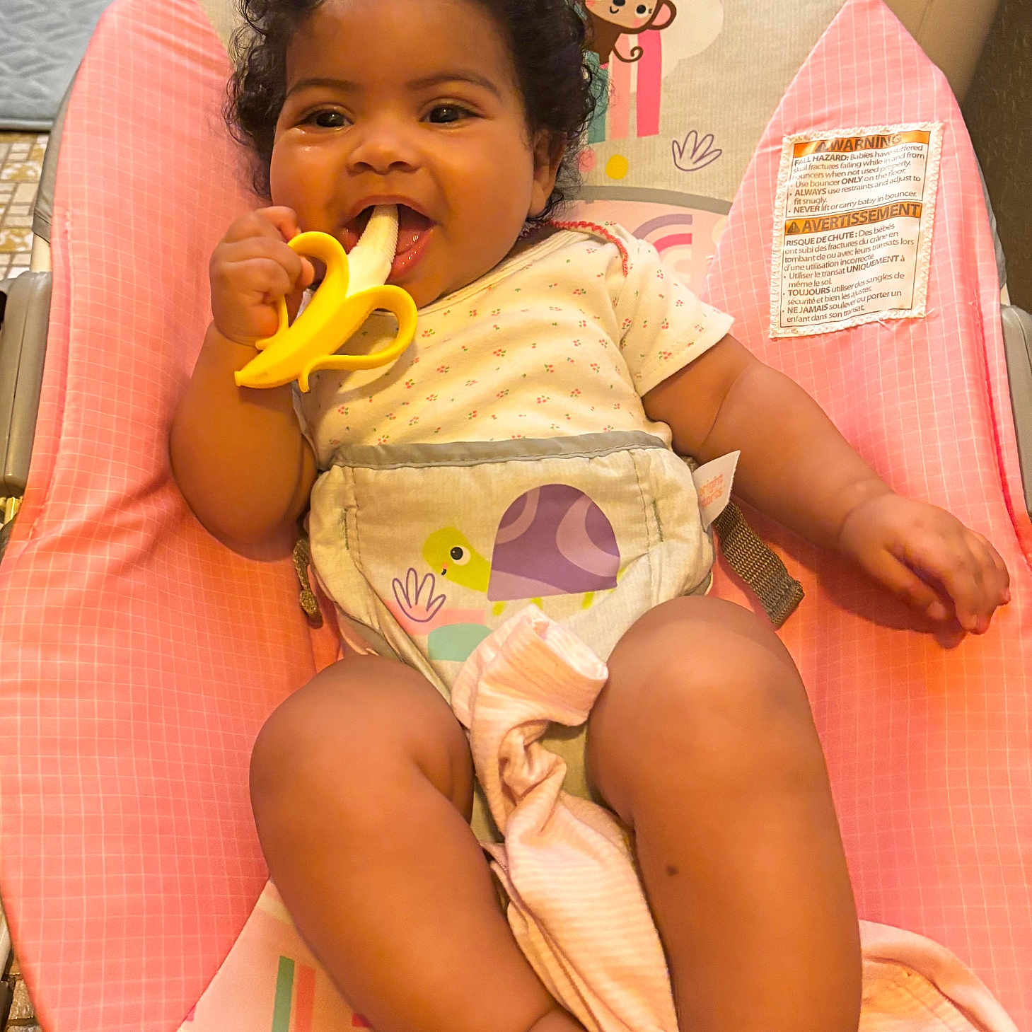 Wavie joined the competition — help win amazing prizes! baby, child, infant, smiling, curly_hair, toy_banana, baby_seat, pink, onesie, harness, turtle_design, happy, chewing, indoors, floor_tiles, appliance, cute, comfortable, sitting, portrait