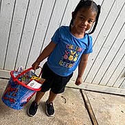 Jamir joined the competition — help win amazing prizes! child, girl, braided_hair, blue_shirt, black_shorts, sneakers, bucket, spiderman, toys, concrete, sidewalk, wall, wooden_wall, outdoor, smiling, standing, casual_clothing, daylight, cute, playful