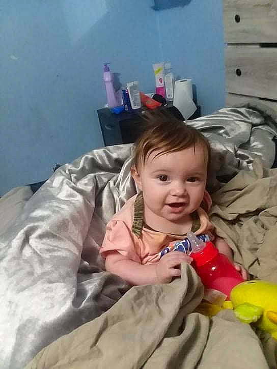 Veronika is registered to the contest to win money with this photo: baby, baby_toddler_clothing, bed, cabinetry, chair, cheek, child, comfort, eye, flooring, fun, fur, happy, iris, linens, mouth, person, room, sitting, smile