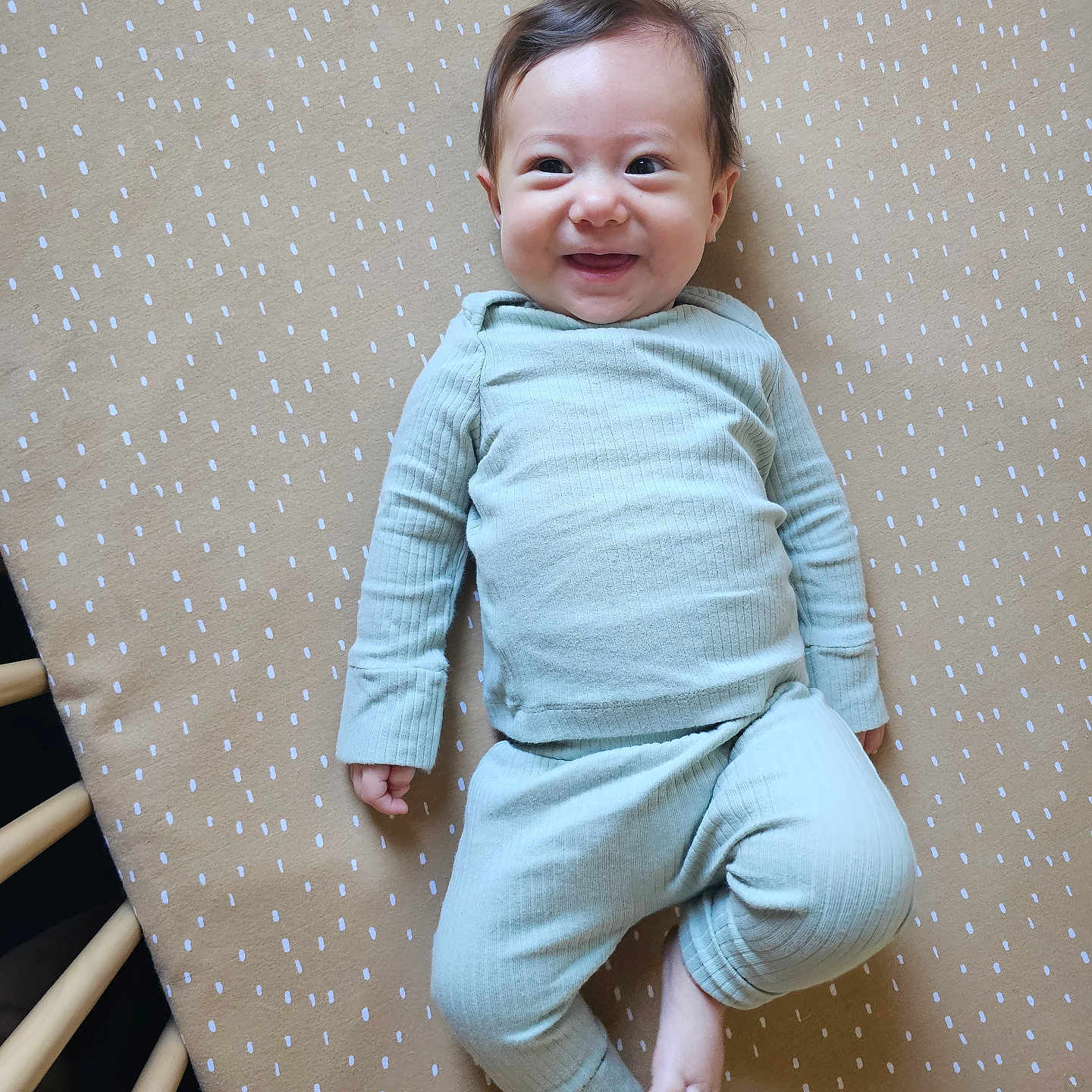 Anastasia is registered to the contest to win money with this photo: baby, infant, smiling, pajamas, crib, mattress, pattern, wood, lying_down, happy, child, cute, indoors, person, face, sleepwear, skin, head, expression, young
