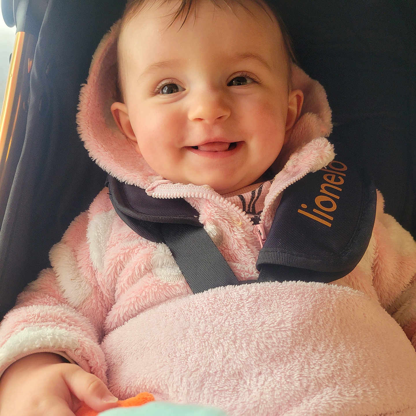Athéna participe au concours pour gagner de l'argent avec cette photo : baby, car_seat, child, child_seat, cozy, cute, face, happy, hooded_jacket, human, indoors, infant, person, pink_jacket, portrait, seatbelt, smiling, soft_texture, toddler, warm_clothing