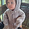 baby, toddler, child, bear_costume, hood, fluffy, furry, onesie, standing, wicker_chair, chair, indoor, window, sunlight, portrait, face, blue_eyes, serious_expression, cozy, cute