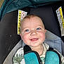 baby, smiling, dinosaur_shirt, car_seat, harness, blue_eyes, child, young_child, cute, happy, infant, seatbelt, strapped_in, warning_label, close_up, portrait, child_safety, casual_clothing, indoor, seat