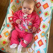 Willow joined the competition — help win amazing prizes! baby, infant, pink_clothing, pacifier, baby_seat, colorful_pattern, wooden_floor, sitting, indoors, child, cute, person, footwear, pacifier_clip, cozy, expression, comfort, clothing, toy, home