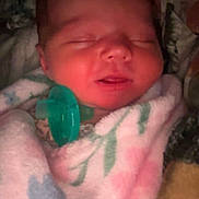 Willow is registered to the contest to win money with this photo: baby, newborn, sleeping, blanket, pacifier, swaddled, closed_eyes, face, portrait, cozy, soft_texture, pink_blanket, floral_pattern, indoor, infant, close_up, peaceful, mouth, head, nursery_item