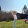 backyard, blue_sky, casual_clothing, child, daylight, fence, grass, happy, long_sleeve_shirt, nature, outdoor, pacifier, pants, playful_pose, shoes, smiling, sunny_day, toys, tree, young_child