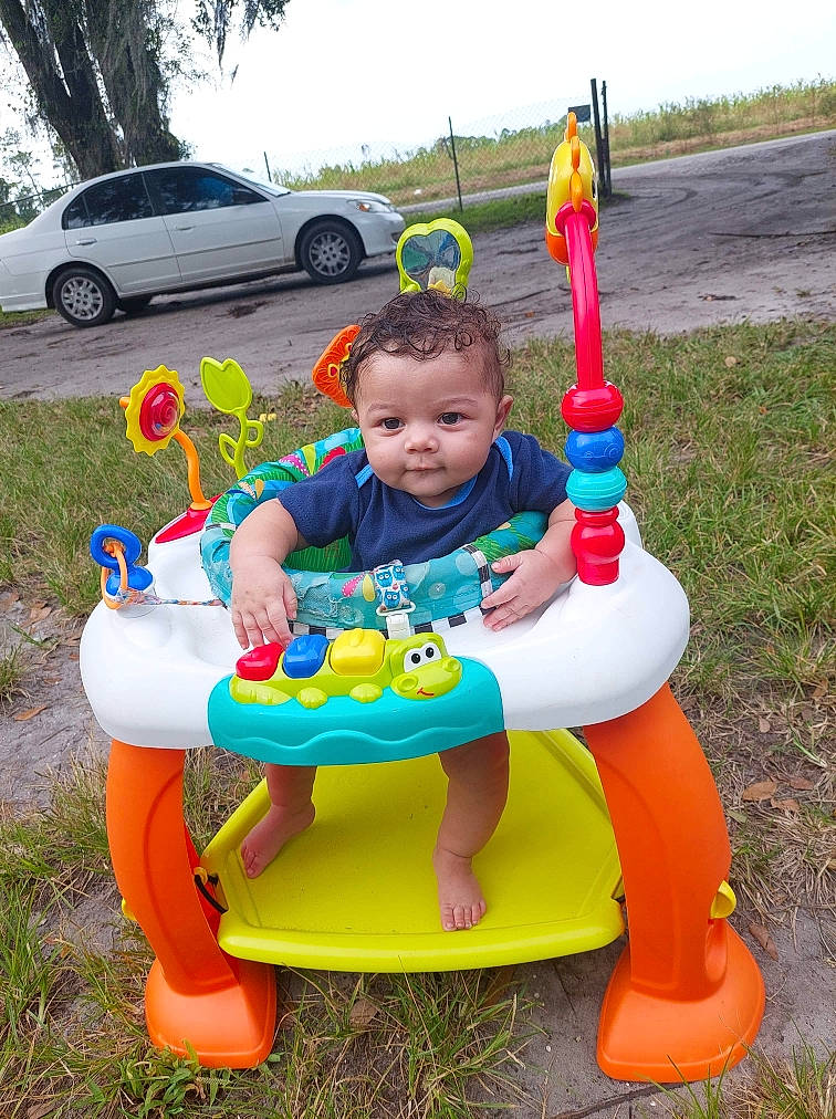Jaysen joined the competition — help win amazing prizes! baby_playing_with_toys, baby_toddler_clothing, car, child, fun, grass, leisure, person, plant, play, recreation, riding_toy, sitting, sky, smile, tire, toddler, toy, tree, vehicle