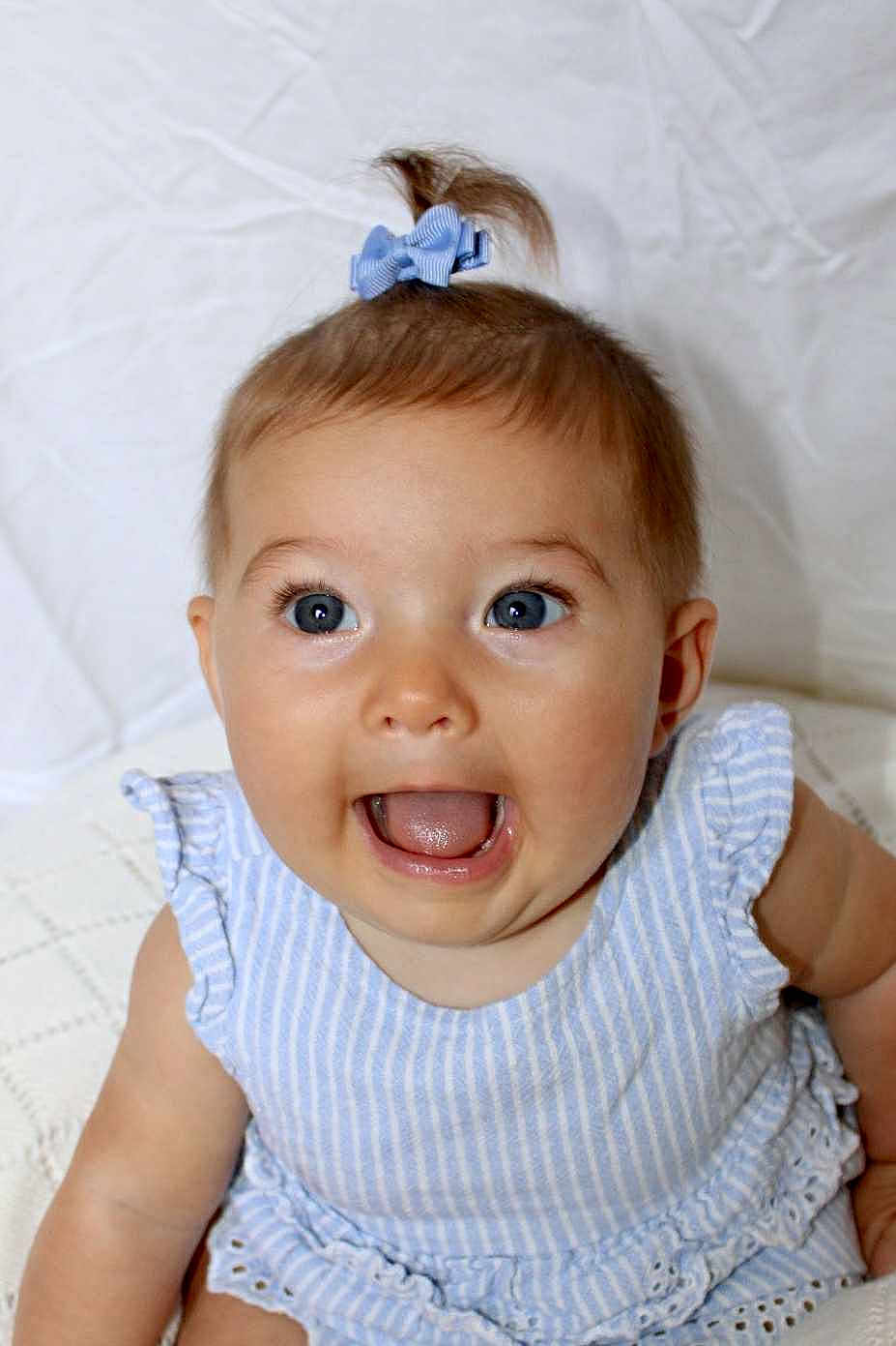 Mylee joined the competition — help win amazing prizes! baby, child, blue_eyes, bow, dress, striped_clothing, smiling, happy, cute, infant, portrait, sitting, white_background, soft_texture, young_child, head_accessory, closeup, innocent, joyful, adorable