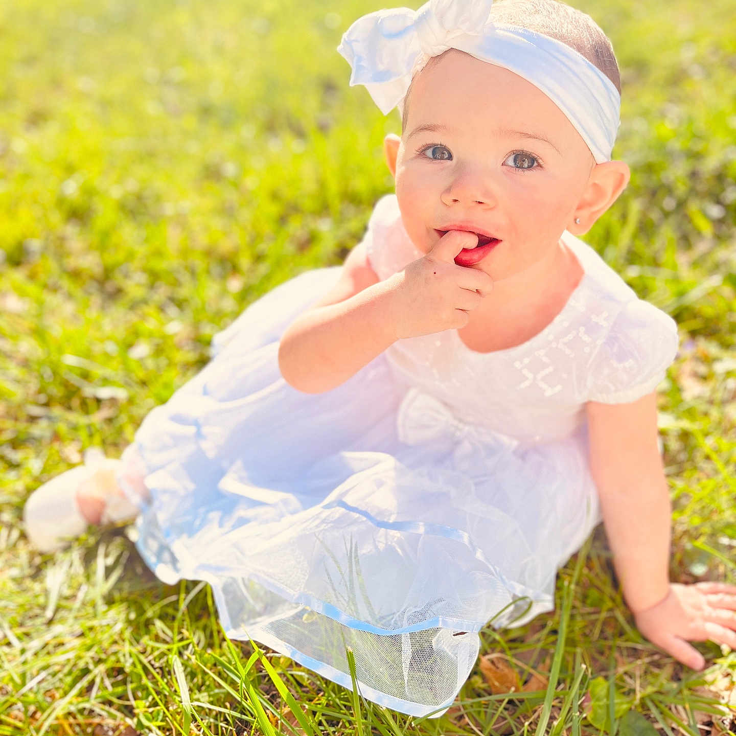 Lilith joined the competition — help win amazing prizes! baby, child, girl, white_dress, headband, grass, outdoor, sunlight, portrait, cute, smiling, sitting, finger_in_mouth, nature, greenery, happy, young_child, one_person, daylight, eyes