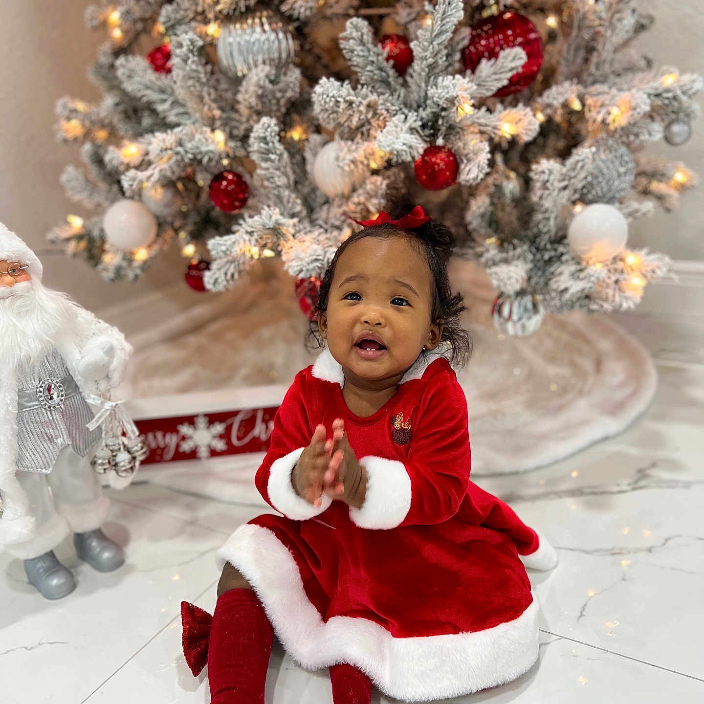 Kattleya joined the competition — help win amazing prizes! celebration, child, christmas_lights, christmas_ornaments, christmas_tree, clapping, cute, decorations, festive_clothing, happy, holiday, indoor, marble_floor, person, red_bow, red_dress, santa_figurine, smiling, toddler, white_fur_trim