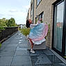 balcony, ballet_pose, brick_wall, building, child, clouds, daylight, dress, footwear, girl, glass_door, glasses, greenery, outdoor, plant, pose, reflection, sky, tiles, window