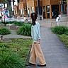 casual_clothing, child, daylight, garden, girl, greenery, lights, modern_architecture, nature, outdoor, pathway, plants, ponytail, public_space, relaxed, side_view, statue, urban, walking, wooden_building