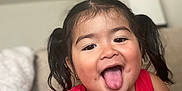 Amy is registered to the contest to win money with this photo: child, toddler, girl, pigtails, red_clothing, smiling, tongue_out, face, indoor, candid, happy, cute, person, hair, playful, portrait, skin, sleeveless, seated, home