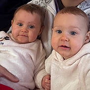 Lyla Et Maya a rejoint le concours — aidez-le/la à gagner de superbes lots ! baby, two_babies, infant, face, blue_eyes, chubby_cheeks, cozy_blanket, hoodie, white_clothing, mickey_mouse, holding_hands, sitting, indoor, couch, family_member, close_up, portrait, soft_texture, hand, adorable