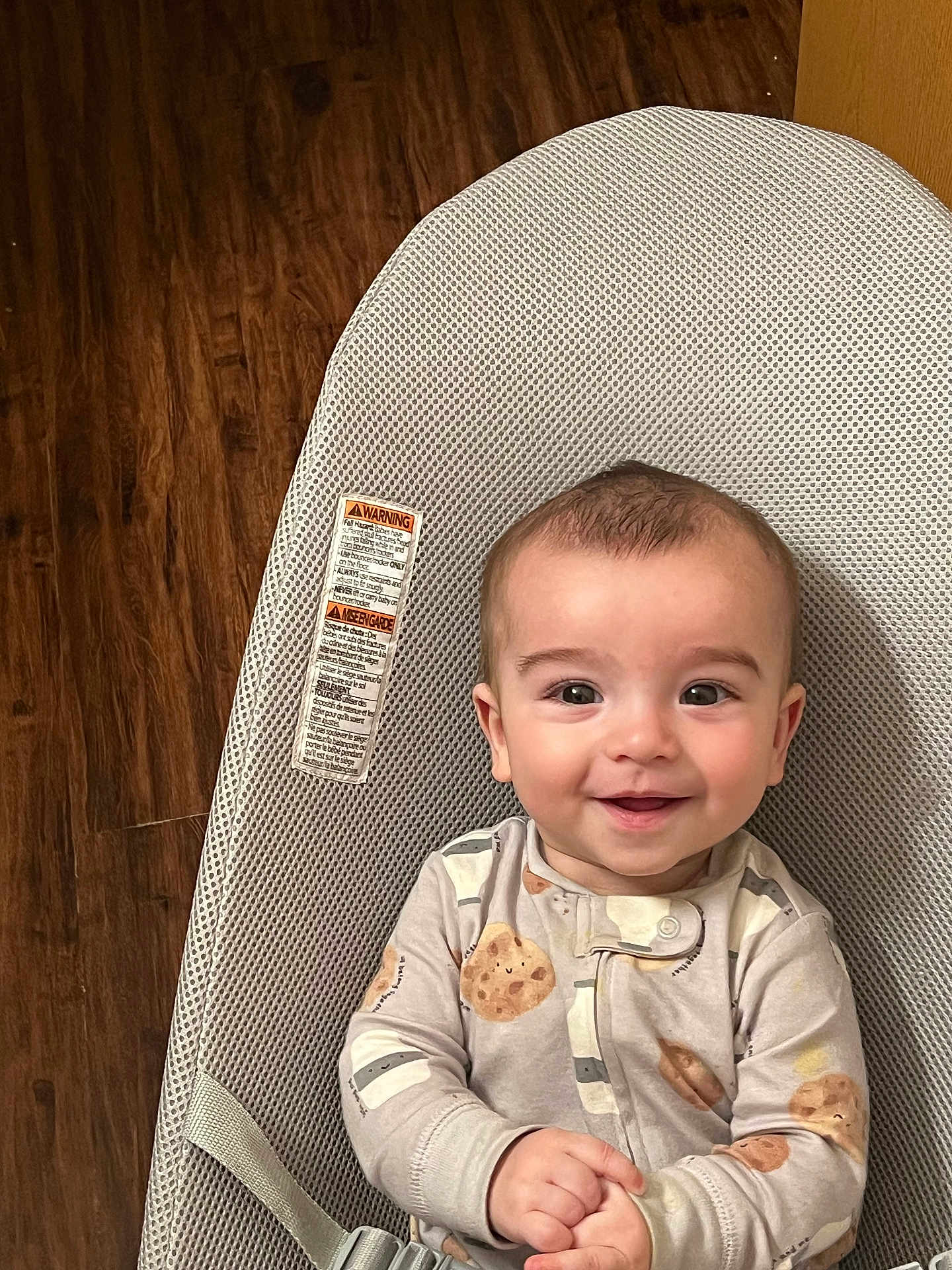 Taytum is registered to the contest to win money with this photo: baby, smiling, face, infant, pajamas, baby_seat, mesh, wooden_floor, happy, child, cute, indoors, clothing, seatbelt, hands, portrait, young_child, one_person, casual, comfort