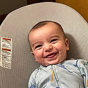 Taytum is registered to the contest to win money with this photo: baby, smiling, infant, onesie, dinosaur_pattern, baby_seat, happy, tongue_out, face, child, cute, indoors, fabric, texture, clothing, portrait, young_child, comfort, seated, joyful