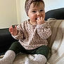 baby, child, infant, pacifier, headband, leopard_print, sweater, socks, blanket, couch, indoor, smiling, cute, seated, cozy, happy, person, portrait, home, soft_lighting