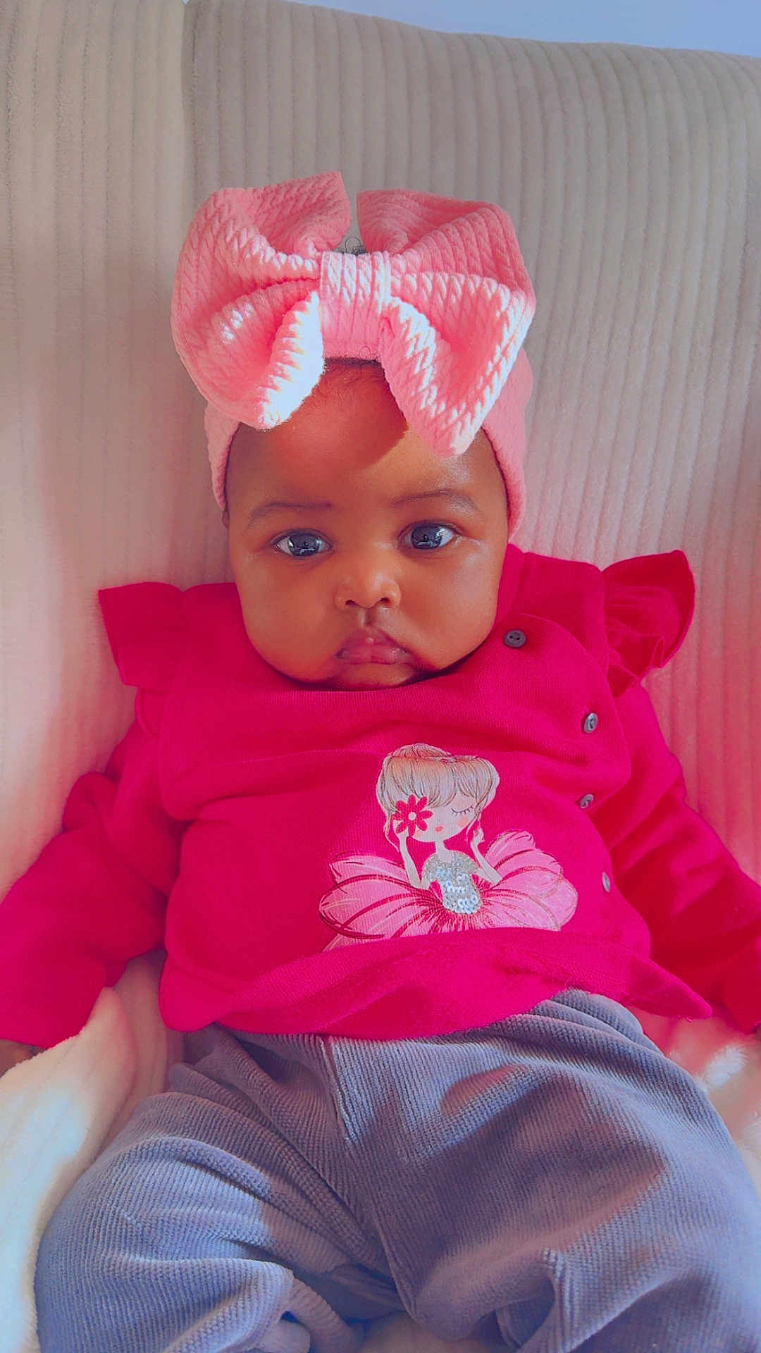 Miya participe au concours pour gagner de l'argent avec cette photo : baby, child, infant, pink_bow, pink_clothing, cartoon_print, blanket, soft_texture, cute, portrait, indoors, seated, serious_expression, headband, chubby_cheeks, clothing, person, face, young_child, cozy