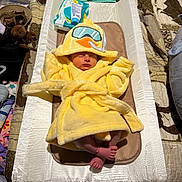 Roper is registered to the contest to win money with this photo: baby, baby_cream, baby_wipes, bedspread, blankets, changing_pad, child, cozy, cute, duck_hood, foot, indoors, infant, newborn, nursery, person, resting, sleeping, soft_fabric, yellow_robe