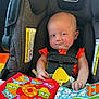 Creed is registered to the contest to win money with this photo: baby, car_seat, evenflo, child, infant, cloth_book, colorful, toy, seatbelt, orange_clothing, hand, face, expression, indoors, fabric, pattern, cute, person, young_child, sitting