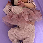 Nashly is registered to the contest to win money with this photo: baby, sleeping, infant, pink_clothing, headband, flower, ruffled_skirt, socks, bows, soft_surface, purple_background, cute, peaceful, newborn, portrait, child, hands, feet, cozy, toddler