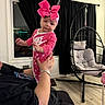 Nashly is registered to the contest to win money with this photo: adult, baby, bow, child, curtains, family, furniture, hands, hanging_chair, headband, holding, indoor, infant, living_room, nike, pink_outfit, portrait, smiling, window, wood_floor