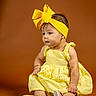 Nashly is registered to the contest to win money with this photo: baby, bare_legs, bow, child, dress, facial_expression, fashion, female, indoor, infant, orange_background, photography, portrait, shoes, sitting, smiling, studio, studio_lighting, yellow_dress, yellow_headband