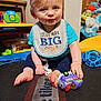 Lennox joined the competition — help win amazing prizes! baby, child, bib, toy_camera, blue_shirt, sitting, indoors, play_mat, toy, foot, hand, face, blond_hair, expression, home_interior, child_toy, pacifier, colorful, cute, infant