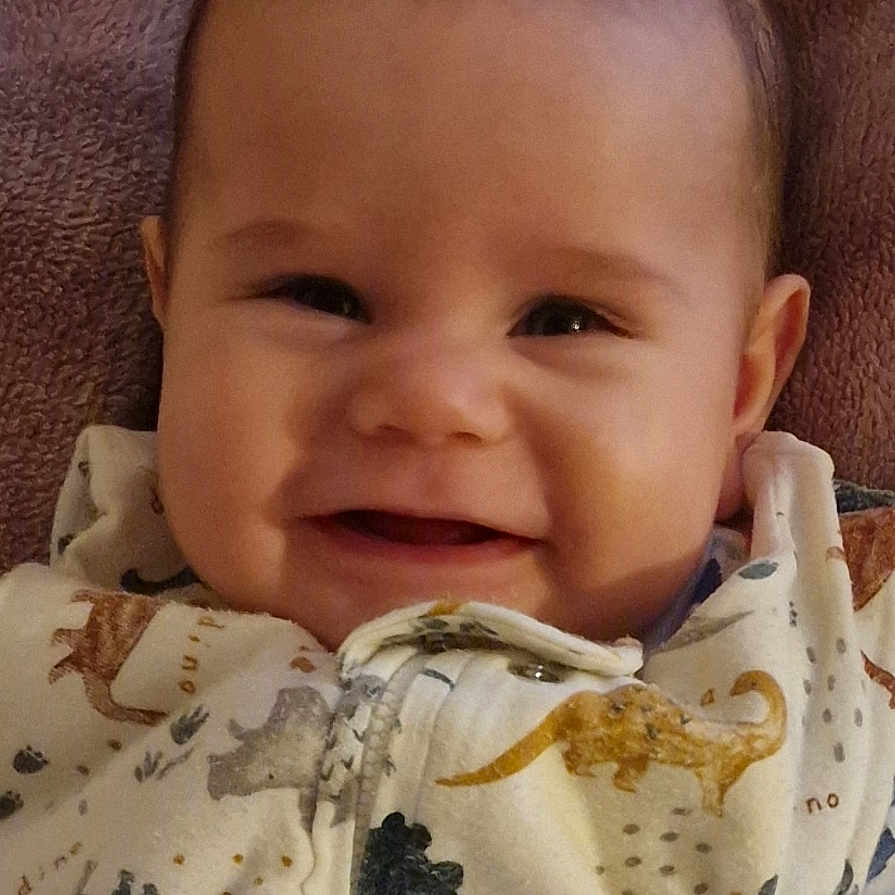 Alexandru Mihail joined the competition — help win amazing prizes! apparel, baby, baby_sleepwear, blanket, child, clothing, cozy, cute, dinosaur_print, face, happy, head, indoors, infant, lying_down, portrait, smile, soft_texture, toddler, warm