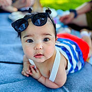 Jasmine joined the competition — help win amazing prizes! baby, child, infant, sunglasses, pigtails, outdoor, blanket, blue, green, grass, cute, portrait, lying_down, summer, sunlight, people, blurred_background, clothing, striped, red