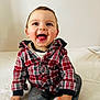 child, baby, toddler, smiling, tongue_out, plaid_shirt, red_plaid, sitting, indoors, white_background, portrait, cute, happy, eyes, hands, jeans, sock, cozy, casual_clothing, playful