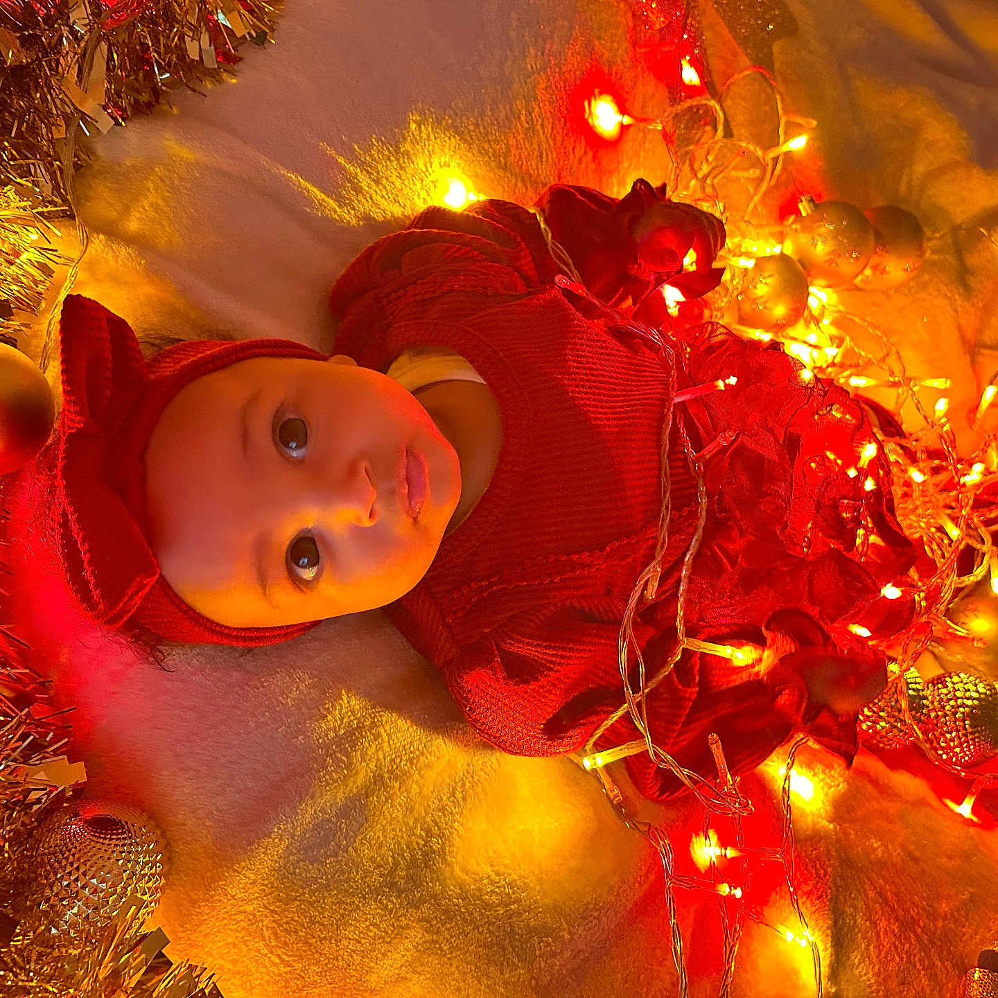Kaysha a rejoint le concours — aidez-le/la à gagner de superbes lots ! baby, blanket, celebration, child, christmas, cute, decorations, face, festive, headband, holiday, indoors, infant, lights, ornaments, portrait, red_clothing, smile, tinsel, warm_lighting